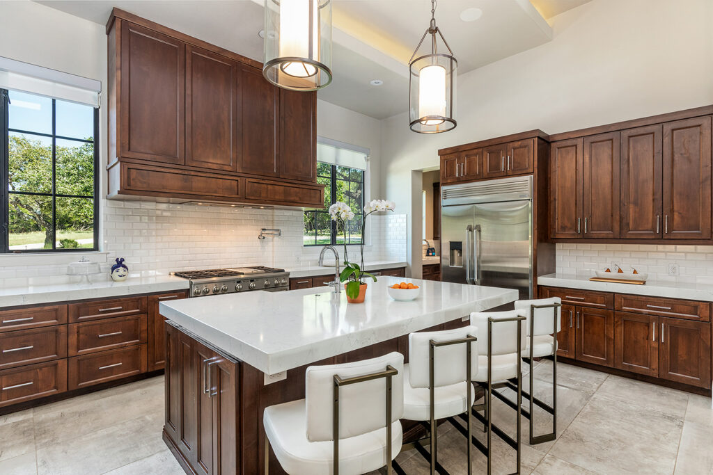 Spacious kitchen with light granite countertops and dark wood cabinets designed by Core Design San Antonio