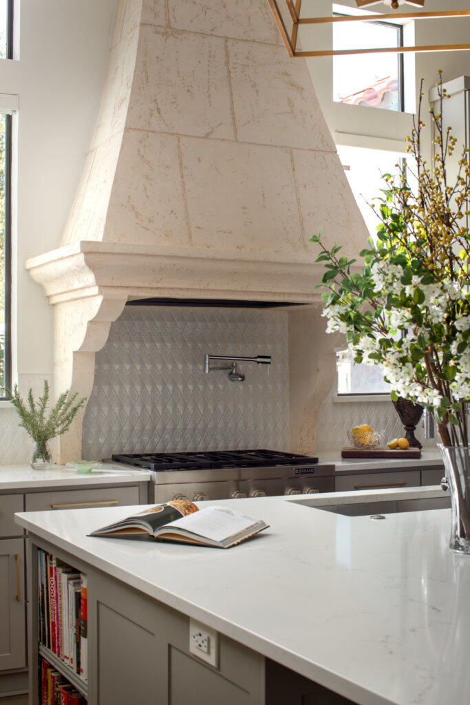 Modern white kitchen with waterfall edge countertop and range hood designed by Core Design San Antonio